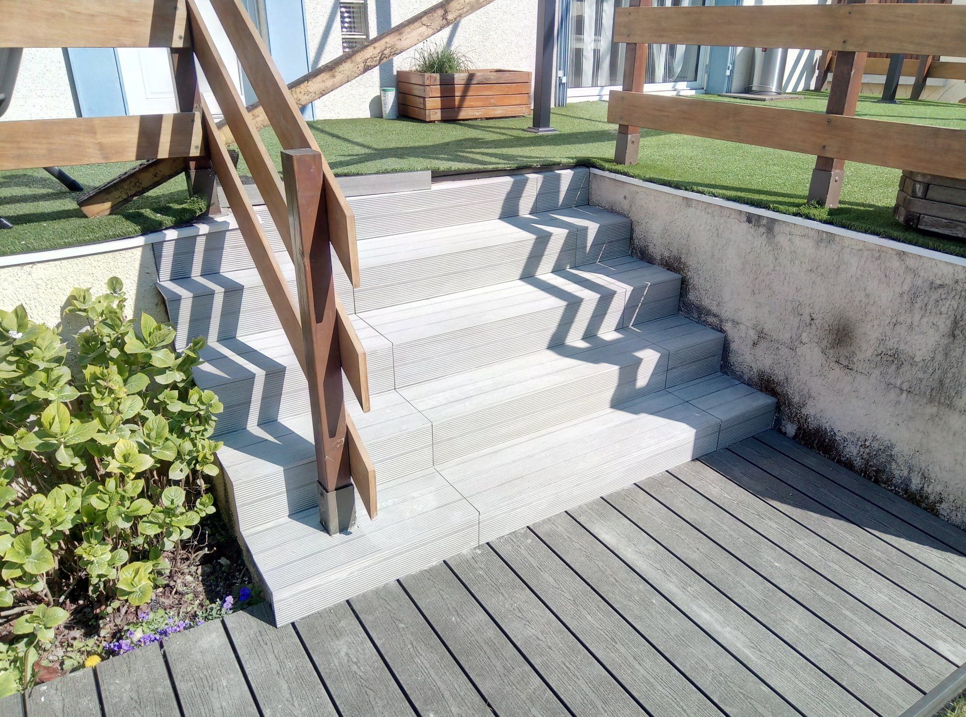 Escalier en bois menant à une terrasse avec une rampe en bois.