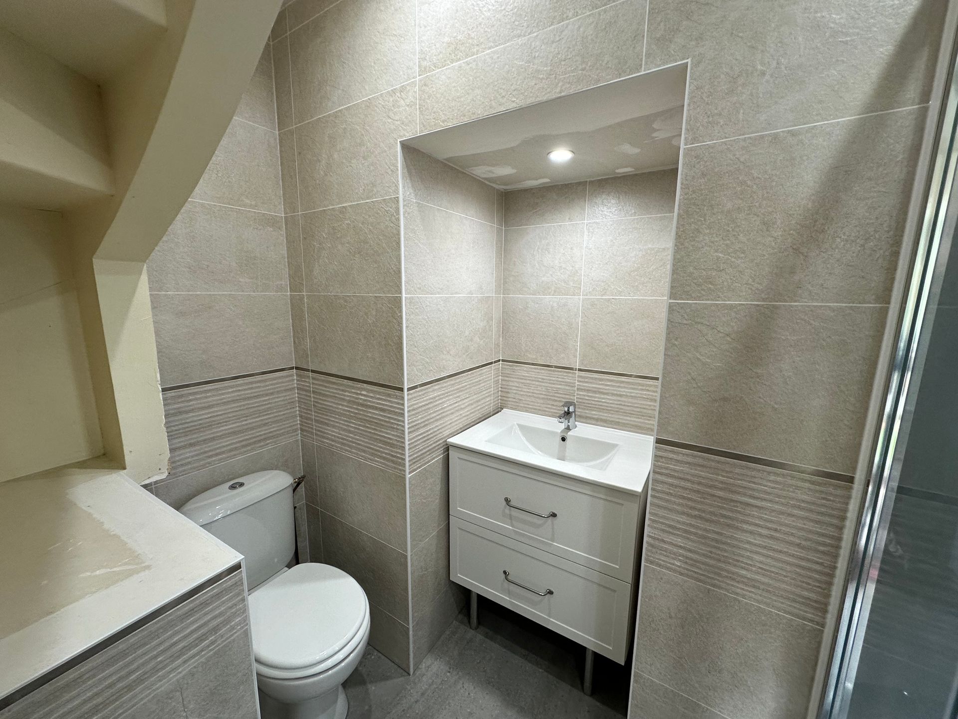 Toilettes dans un angle avec un une vasque sur le coté