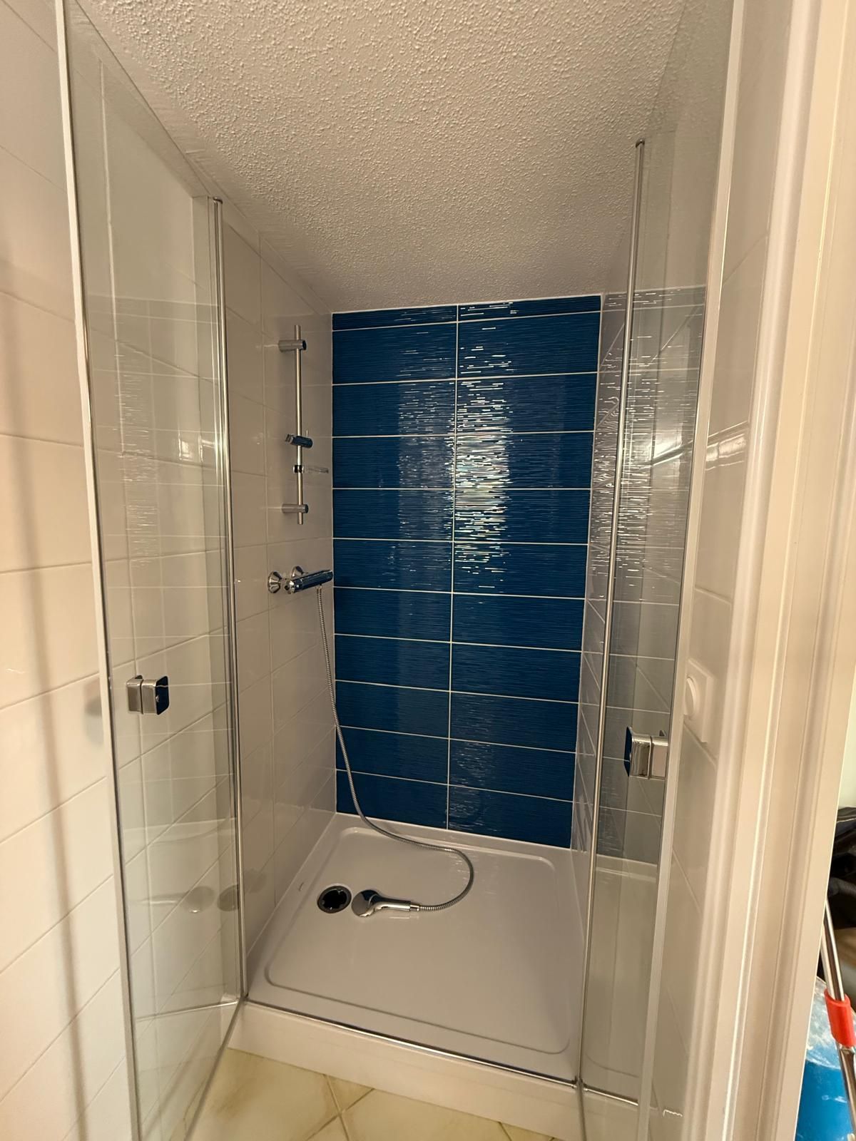Cabine de douche avec une porte et un carrelage bleu