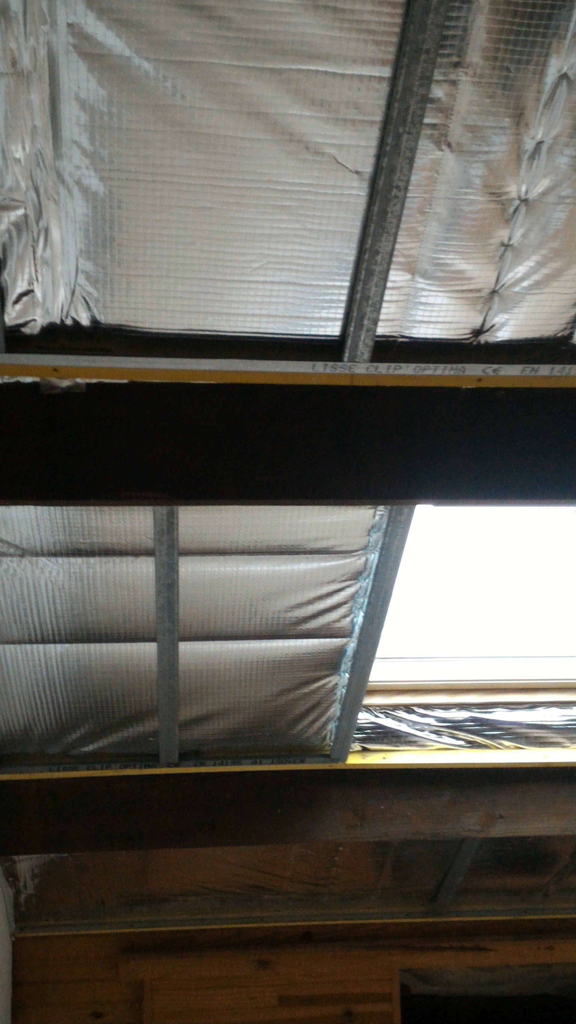 Poutre métallique et plafond isolé. Isolation argentée, poutres et puits de lumière dans un bâtiment.