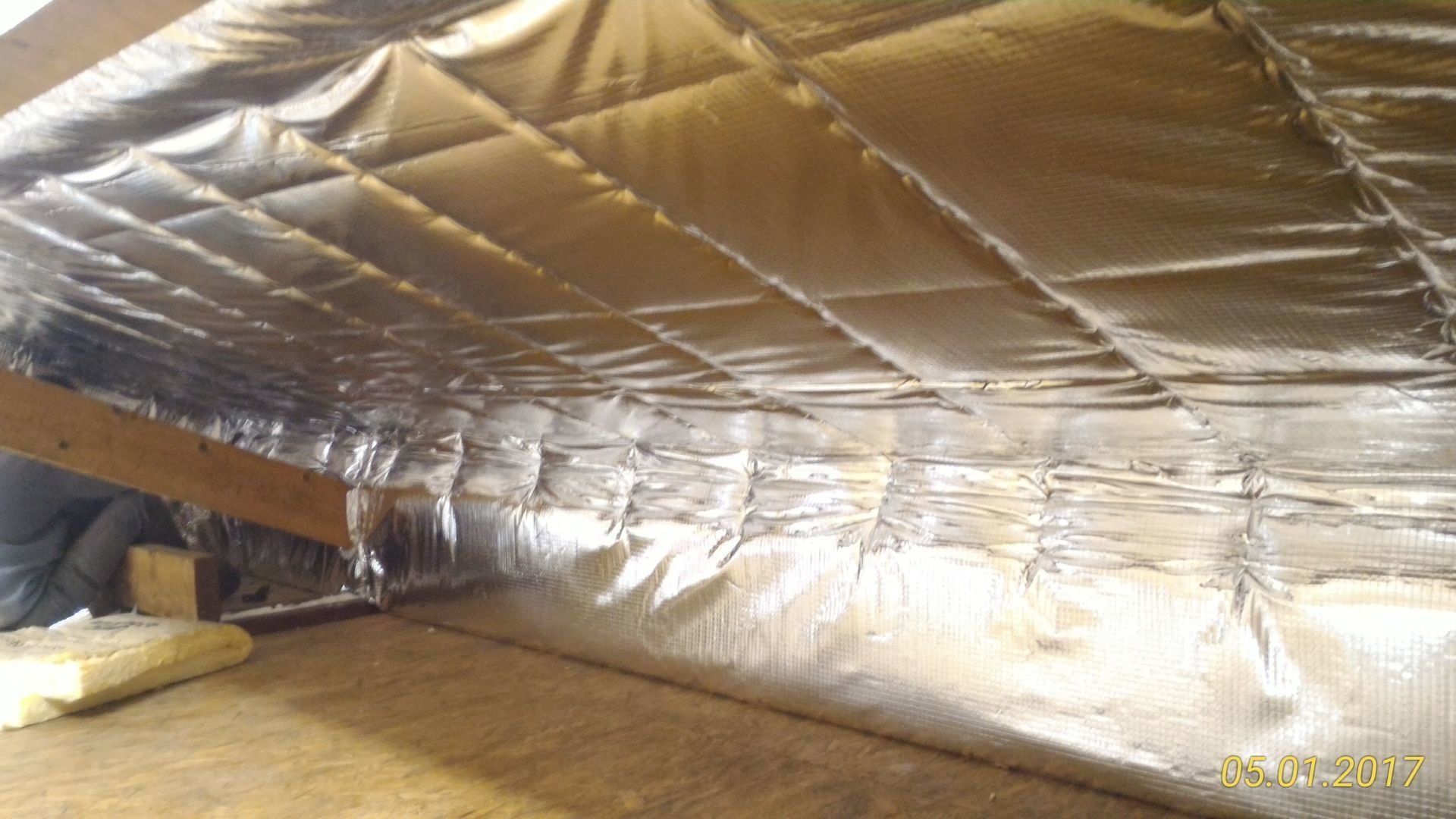 Isolation en feuille d'argent installée sur un plafond de grenier avec poutres en bois.