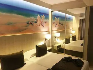Dormitorio con dos camas, armario con espejo y cuadro de playa. Combinación de colores marrón y beige.