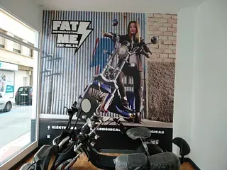 Un scooter eléctrico en exhibición en una tienda, con un gran anuncio en la pared que muestra a una mujer en una motocicleta.