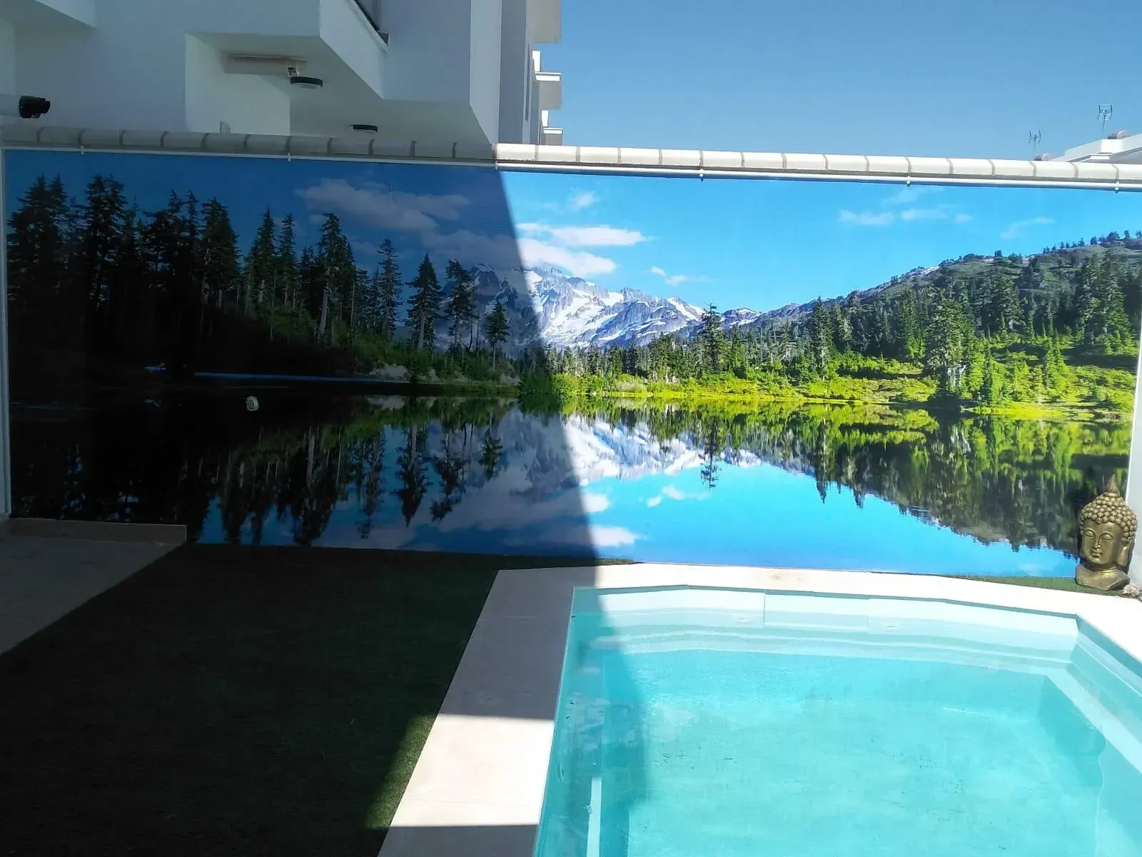 Un área de piscina con grandes paneles escénicos que representan un lago y montañas que reflejan el cielo.
