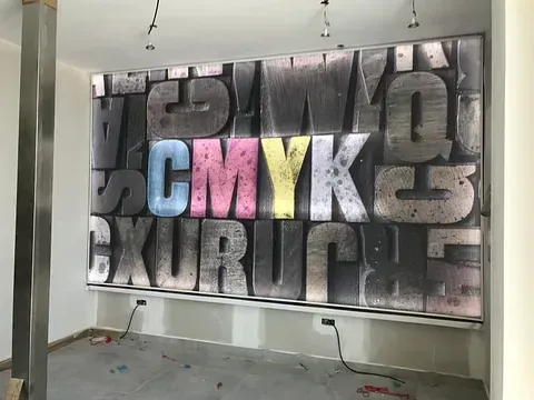 Arte de pared de gran tamaño con la ortografía CMYK en letras coloridas y otras letras grises a su alrededor.