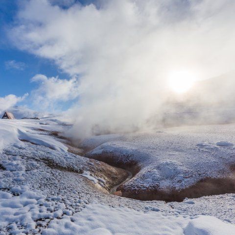 Snjór og gufa. Landslag þar sem sólin skín í gegnum skýin