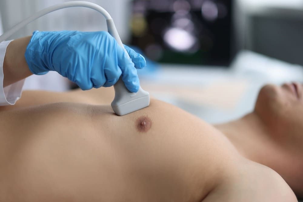 Ein Mann lässt von einem Arzt eine Ultraschalluntersuchung der Brust durchführen.