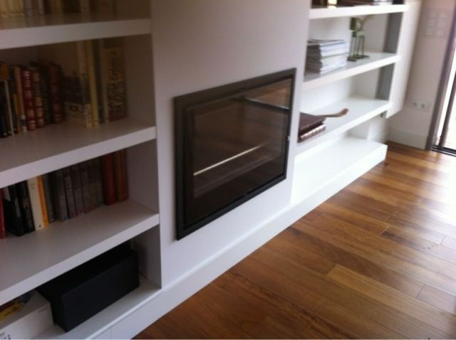 Una sala de estar con chimenea y estanterías.