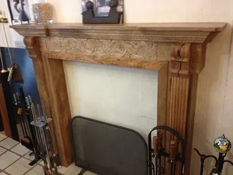 Una chimenea con una repisa de madera y un cuadro encima.