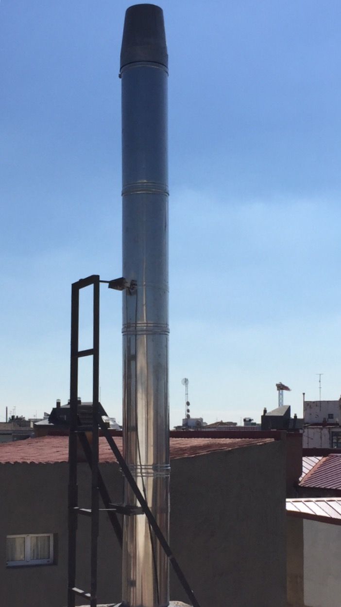 Una chimenea de acero inoxidable en la parte superior de un edificio con una escalera unida a ella.