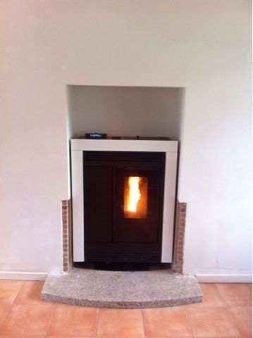 Una chimenea con una estufa de pellets en su interior