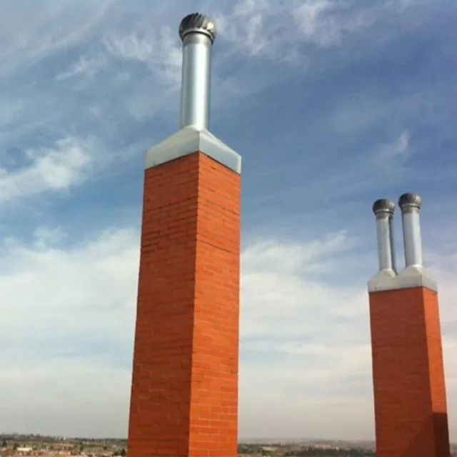 Dos chimeneas de ladrillo contra un cielo azul con nubes