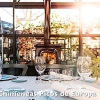 Una mesa con copas de vino y una chimenea al fondo.