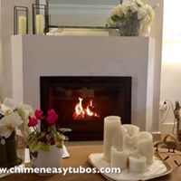 Una chimenea con velas y flores delante de ella en una sala de estar.