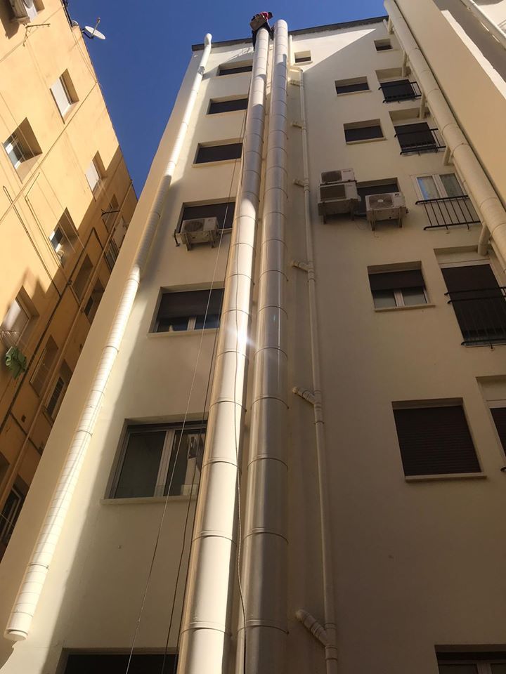 Un hombre está parado en el costado de un edificio alto.