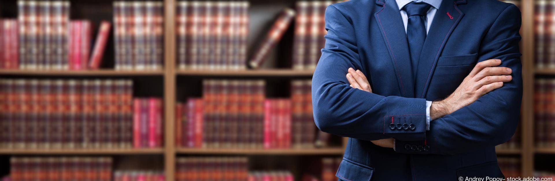 Kompetenter Anwalt mit Anzug vor Bücherregal