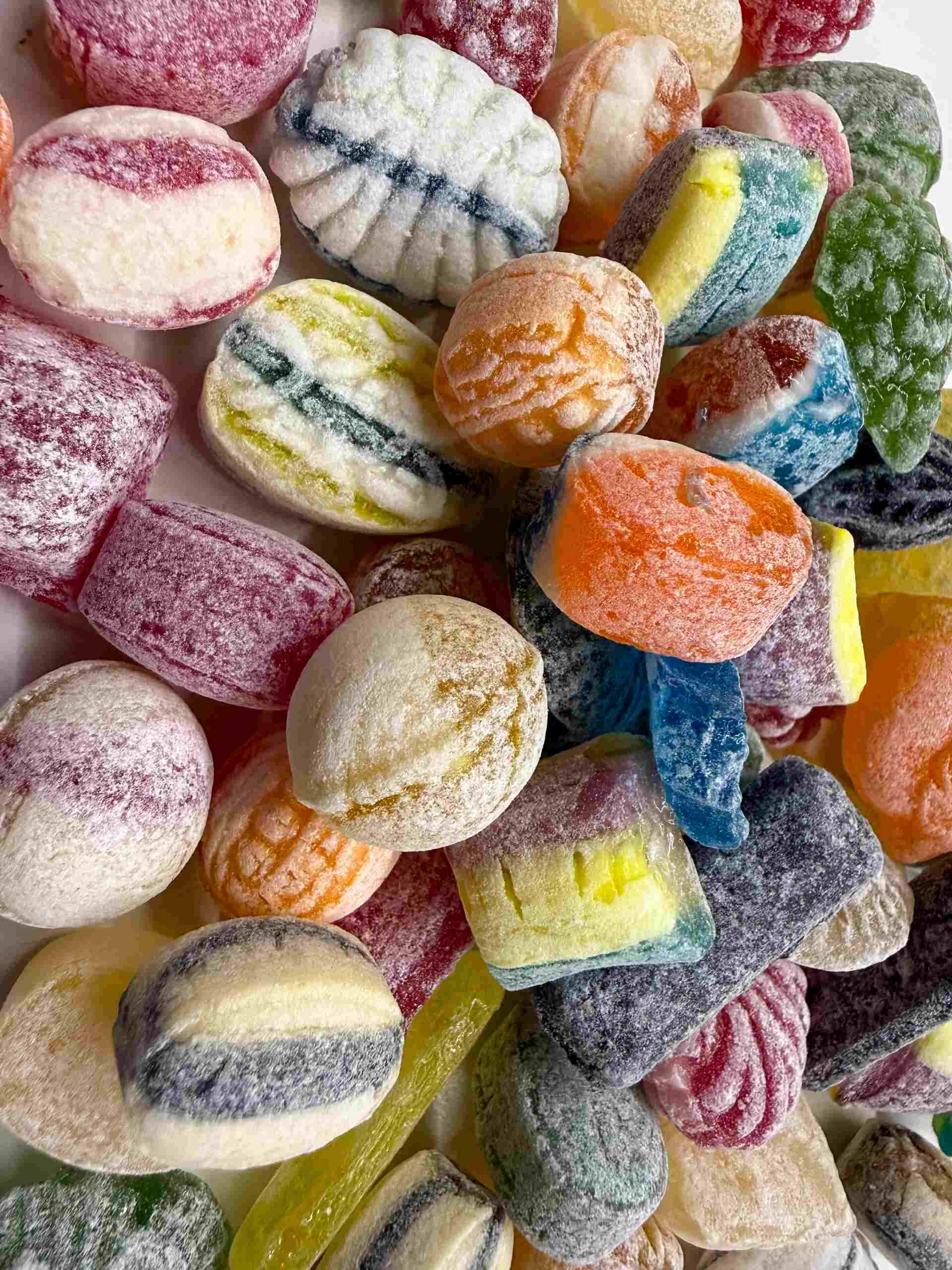 Verschiedene bunte, gestreifte und puderzuckerartige Bonbons, die in einer Nahaufnahme zusammengestapelt sind