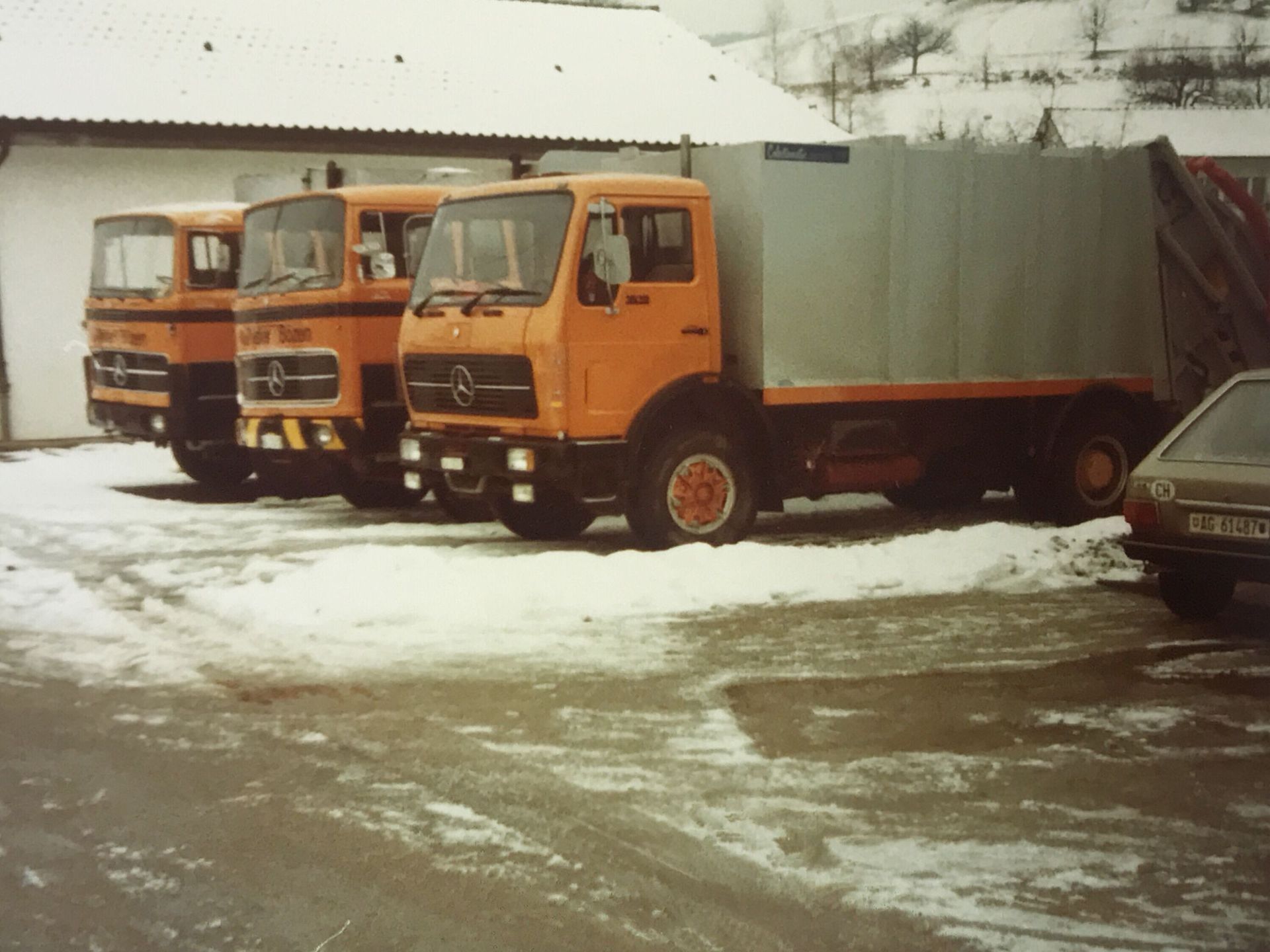 Drei orangefarbene Mercedes-Lkw parkten im Schnee.