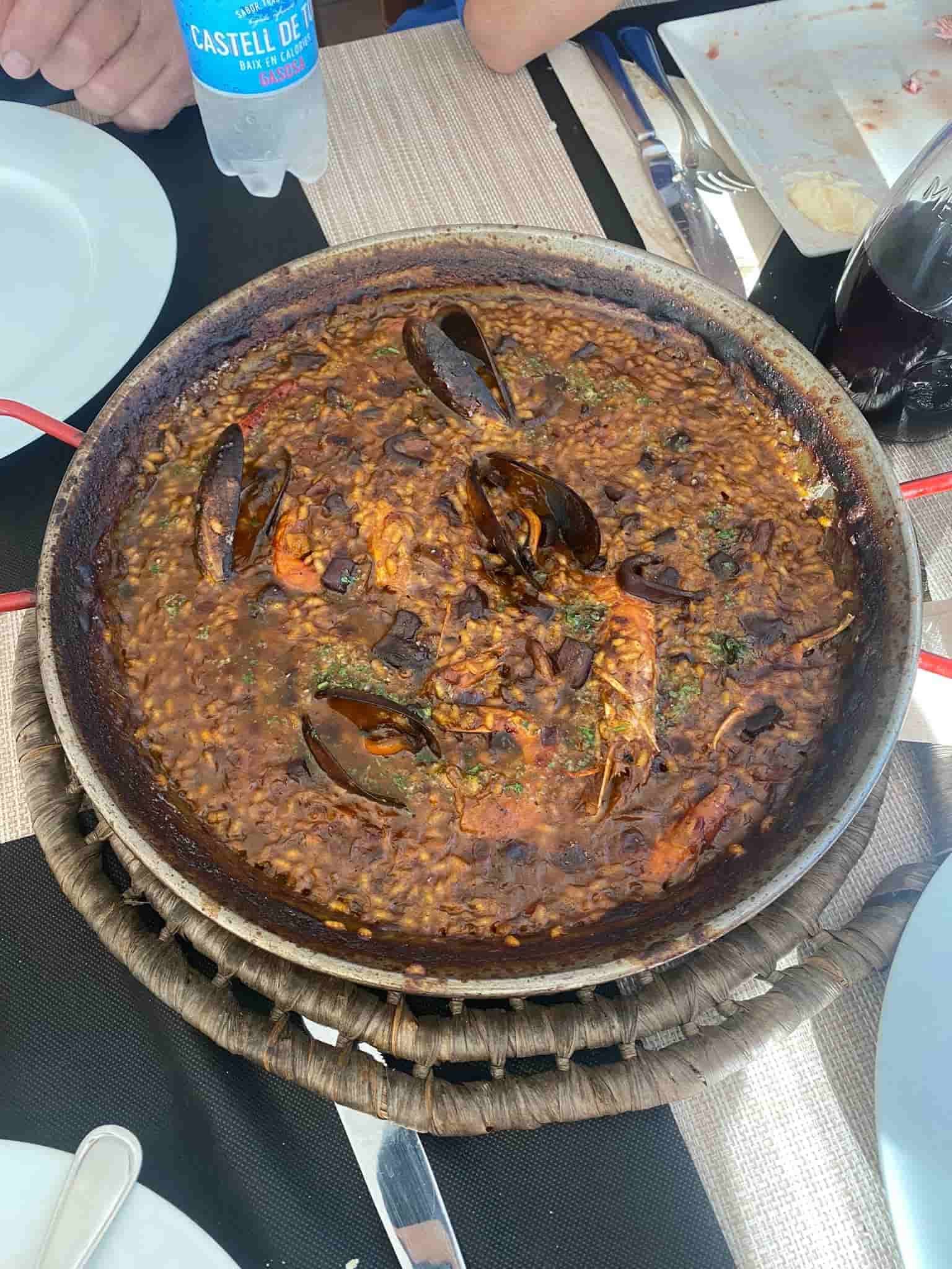 Plato de mariscos fritos sobre una mesa, junto a un vaso de bebida roja. Ambiente de restaurante.