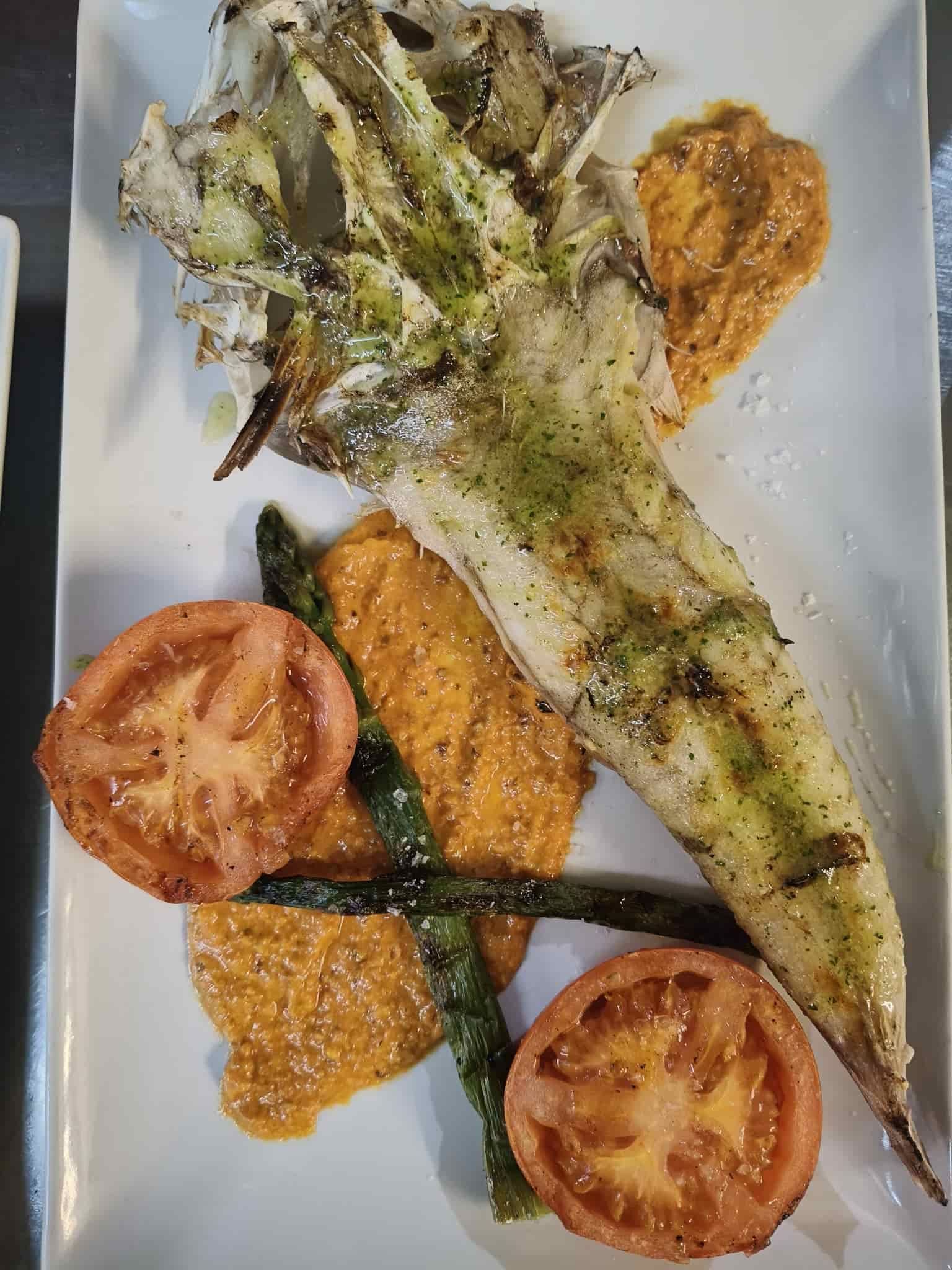 Plato de verduras a la parrilla: espárragos, tomates, salsa romesco y cebolla a la parrilla.