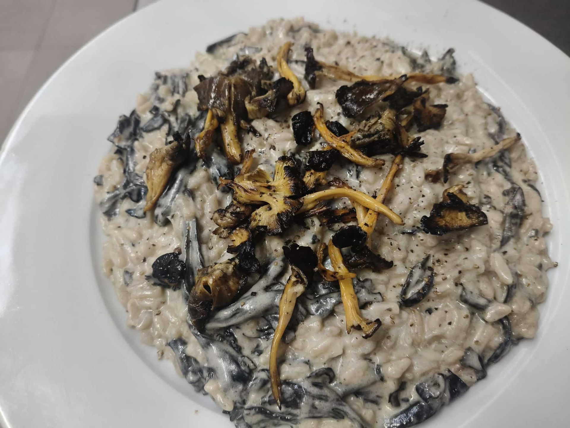 Caracoles al horno en una cazuela de barro marrón, primer plano. Salsa rojiza y conchas visibles.