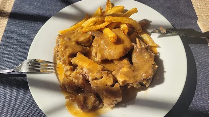 Plato de comida con carne, salsa y patatas fritas.