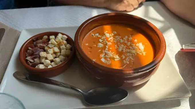 Sopa de tomate con crutones y jamón en un ambiente de restaurante.