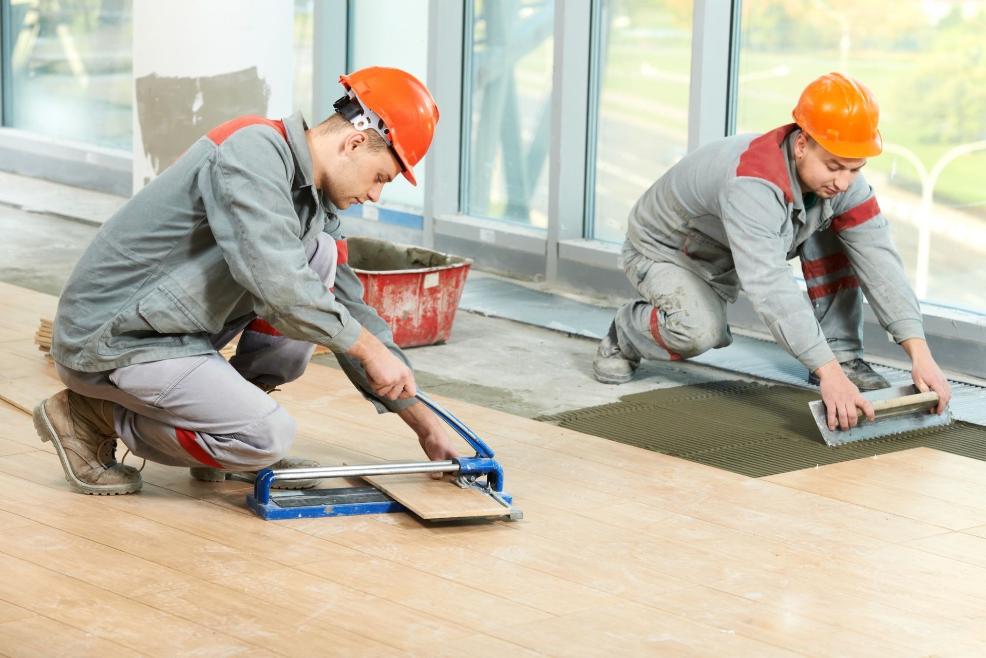 Dos hombres están instalando baldosas en un piso de madera.