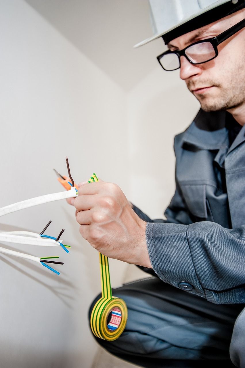 Un hombre que lleva casco y gafas está trabajando con cables eléctricos.