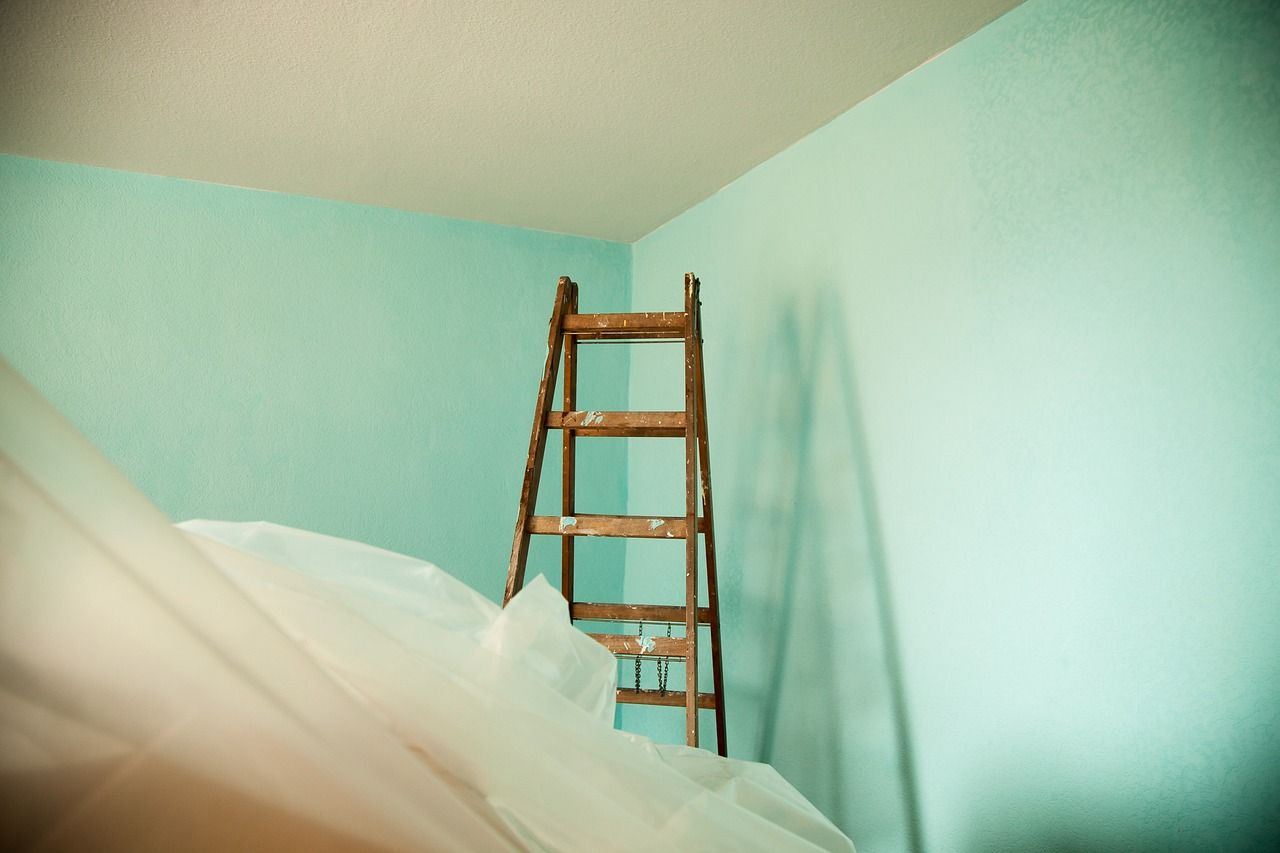 Una escalera de madera está en la esquina de una habitación con paredes azules.
