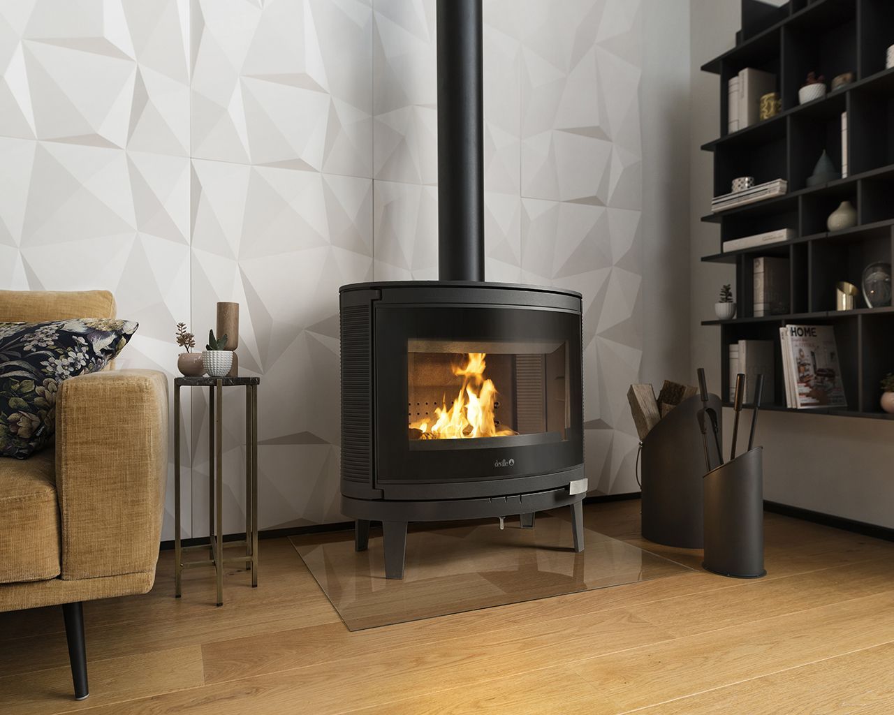 Un poêle à bois moderne, avec un feu allumé, repose sur un tapis de sol en verre contre un mur blanc texturé, à côté d'une bibliothèque.