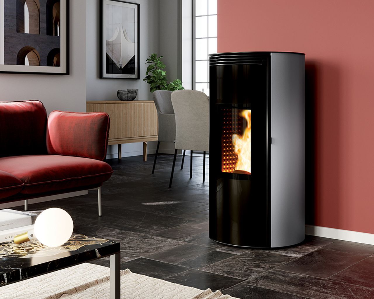 Un poêle à granulés cylindrique moderne, aux finitions argentées et noires, est installé dans un salon, contre un mur rose foncé.