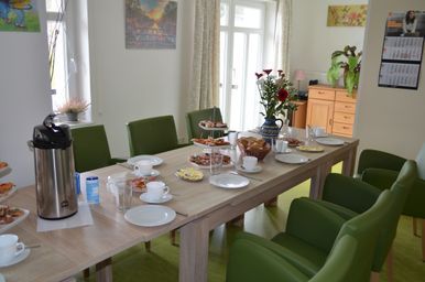 Fitnesstrainerin sitzt vor einer Gruppe Senioren in Sportklamotten