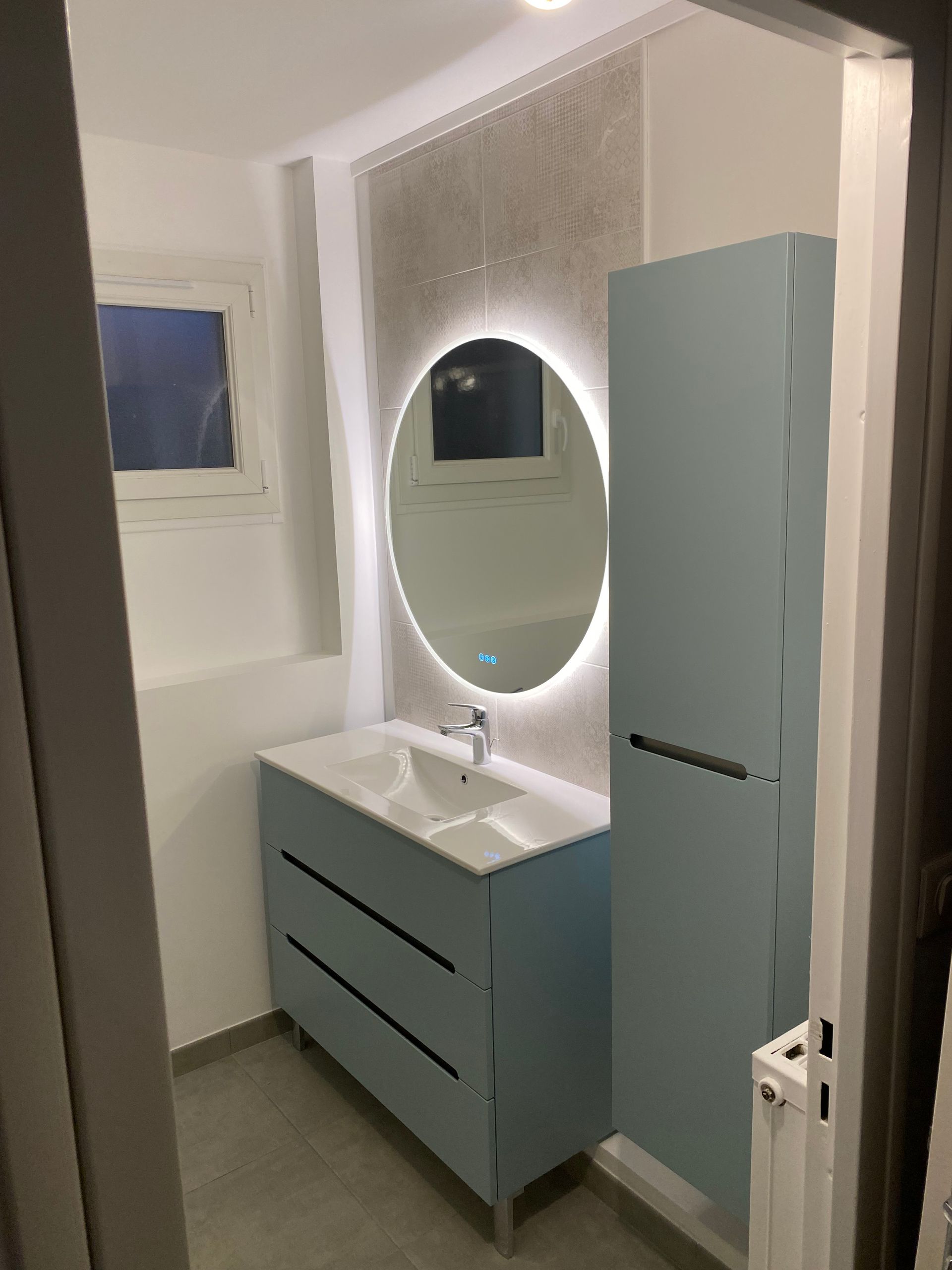 Salle d'eau rénovée avec des meubles et un miroir à LED