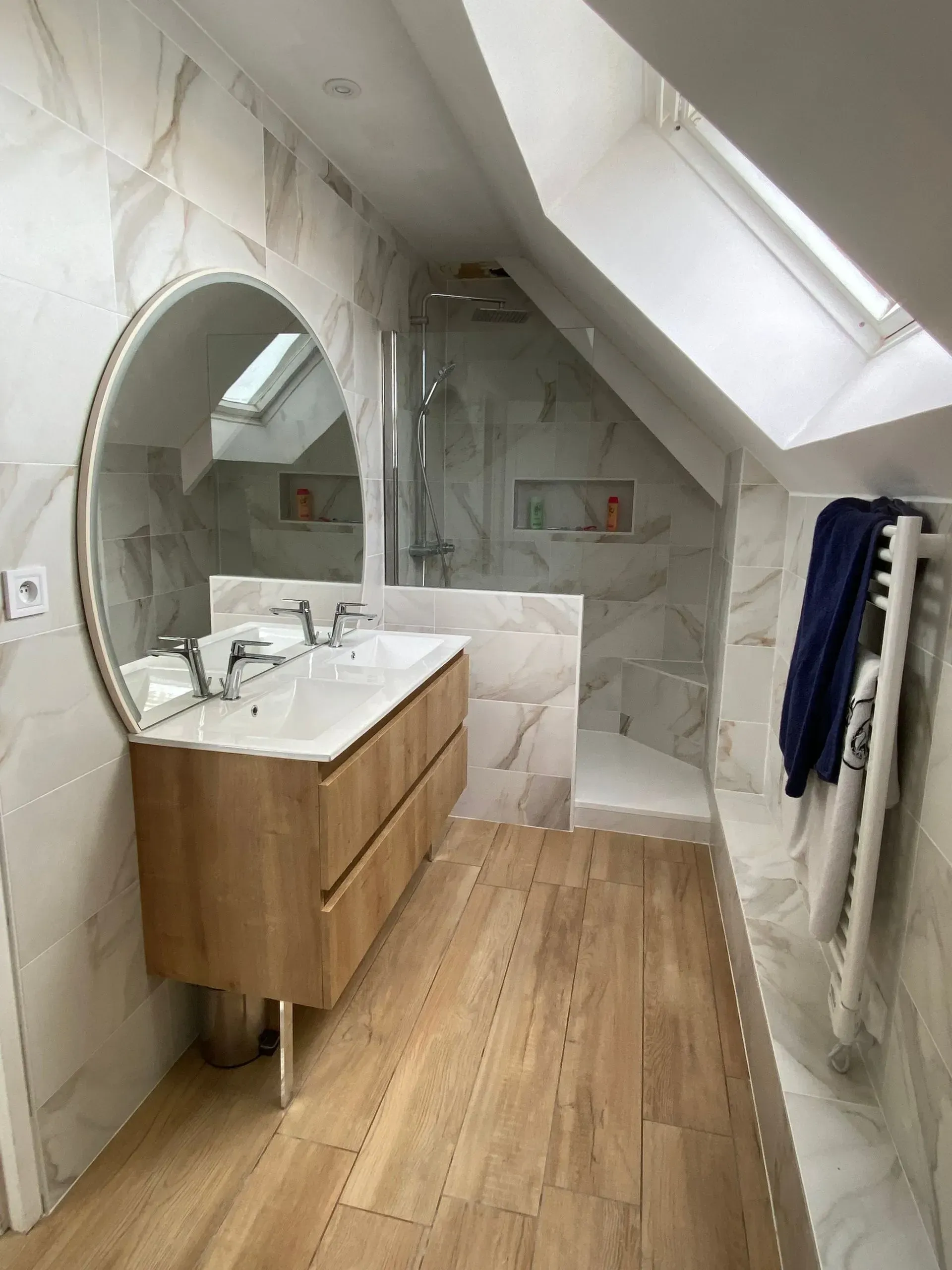 Salle de bains en sous pente après rénovation, vue d'ensemble sur la douche, le meuble vasque, la fenêtre de toit