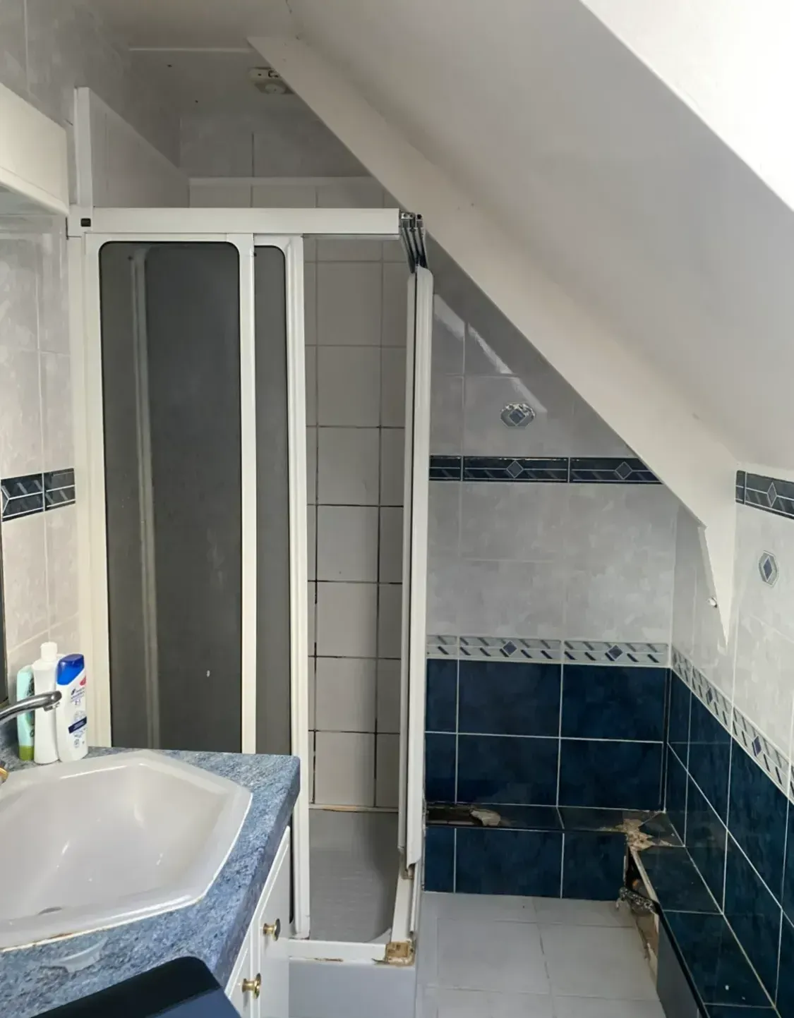 Salle de bains sous pente avant rénovation avec une vue sur la douche