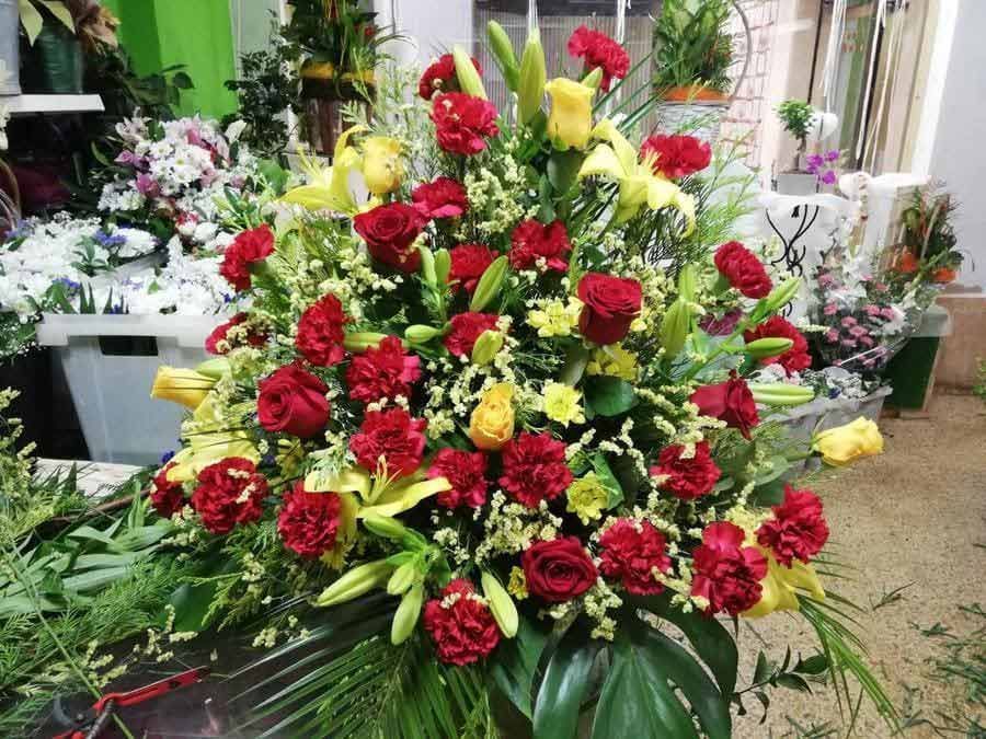 Un gran ramo de flores rojas y amarillas está sobre una mesa.