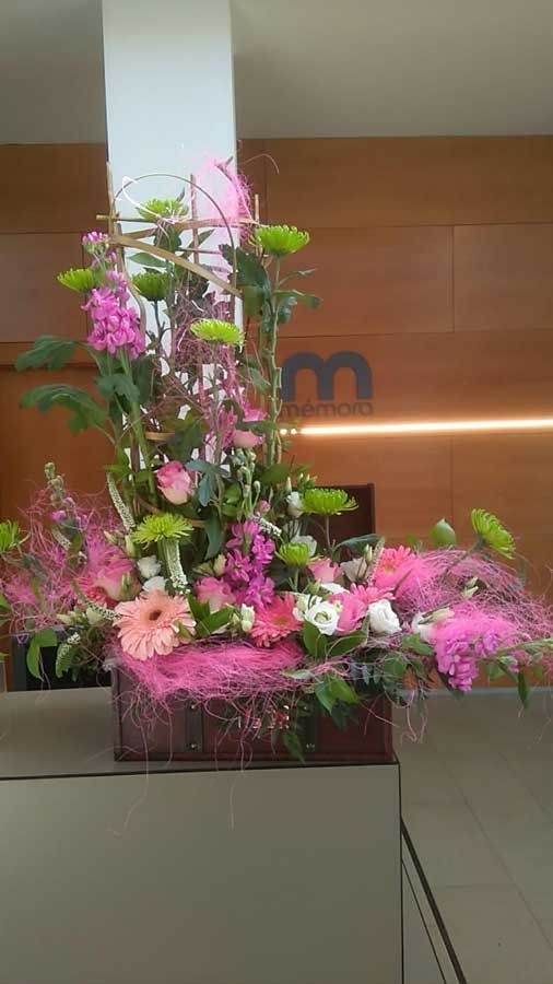 Un gran ramo de flores rosas está sobre una mesa frente a una pared de madera.
