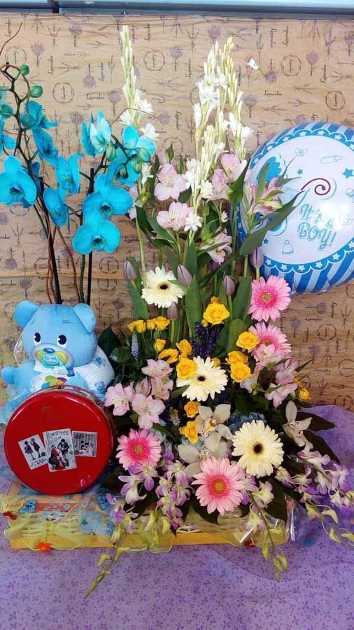 Un osito de peluche está sentado junto a un ramo de flores y globos.