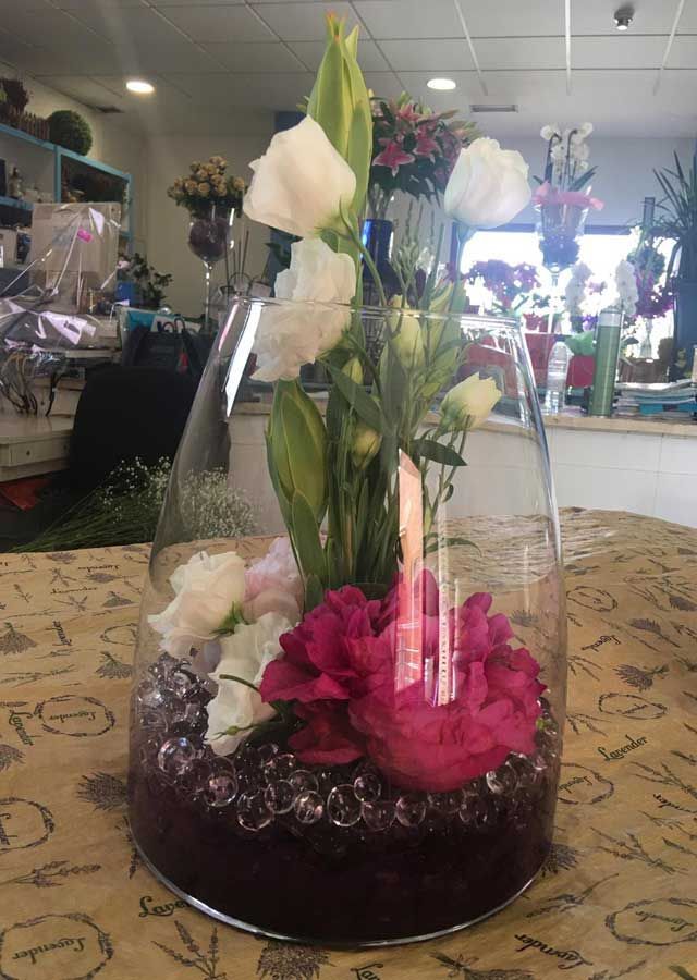 Un jarrón de cristal lleno de flores está sobre una mesa.