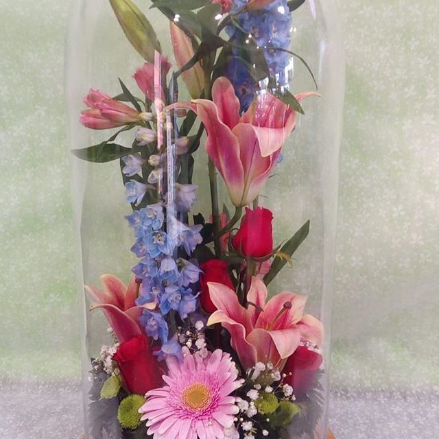 Un recipiente de vidrio lleno de flores rosas y azules.