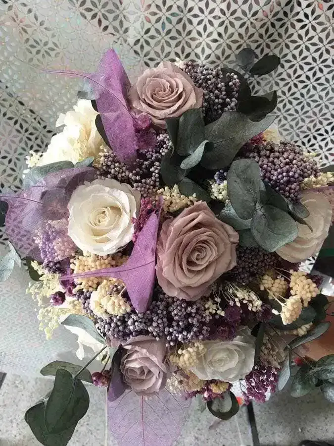 Un ramo de flores moradas y blancas está sobre una mesa.