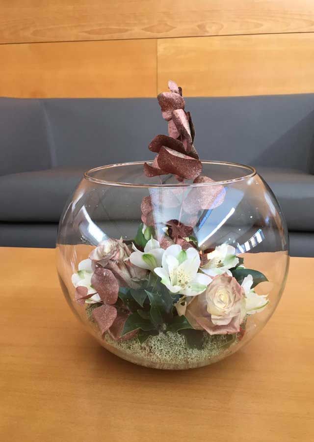 Un cuenco de cristal lleno de flores está sobre una mesa.