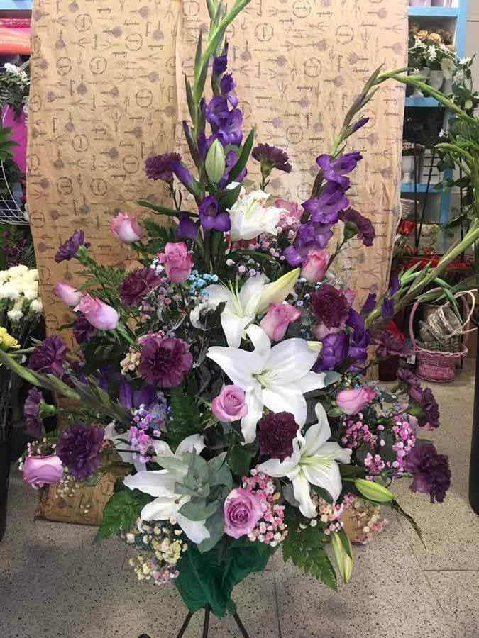 Un gran ramo de flores de color púrpura y blanco en un soporte.