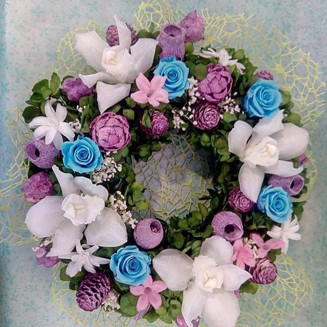 Una corona de flores moradas y azules sobre un fondo azul.