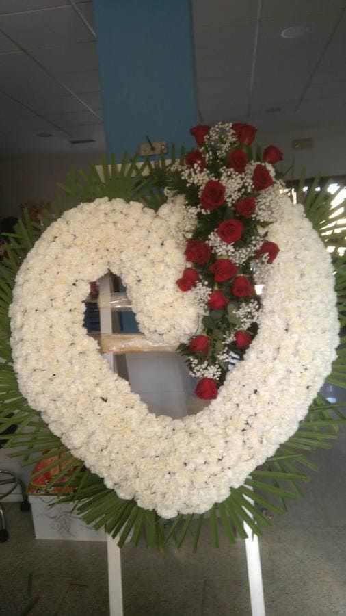 Una corona en forma de corazón hecha de flores blancas y rosas rojas.