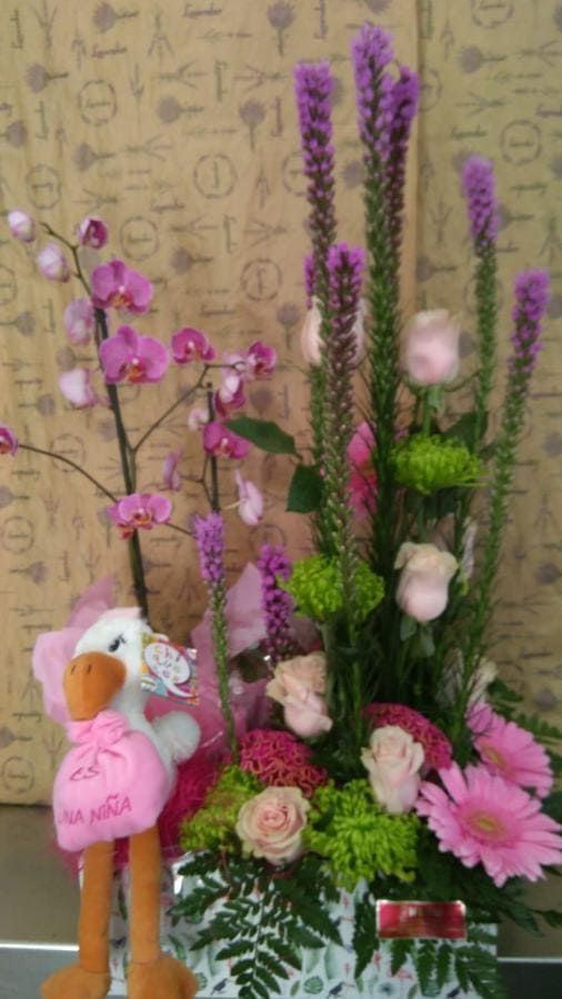 Una cigüeña de peluche está sentada junto a un ramo de flores.