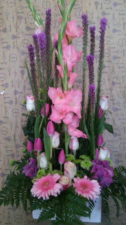 Un ramo de flores rosas y moradas en un jarrón blanco.