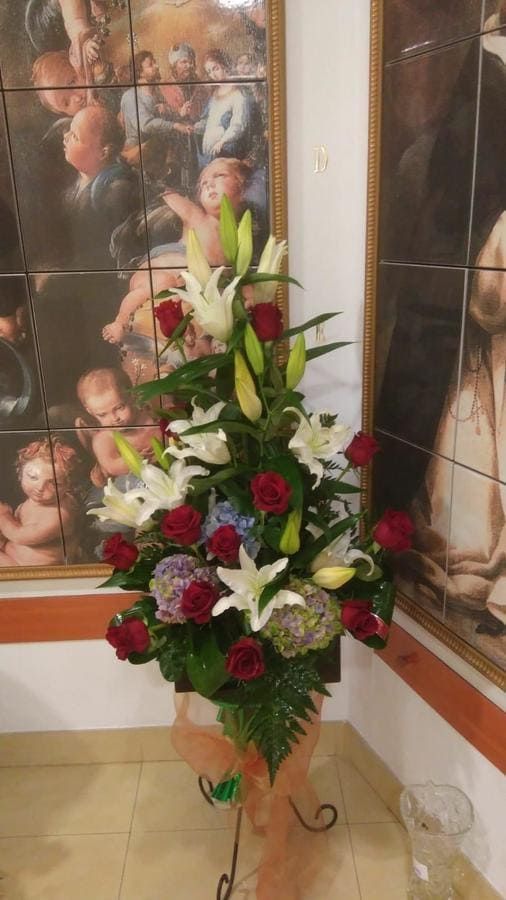 Un jarrón lleno de flores está delante de un cuadro.