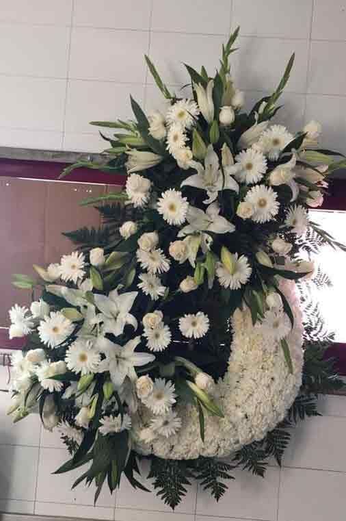 Una corona de flores blancas cuelga en una pared.